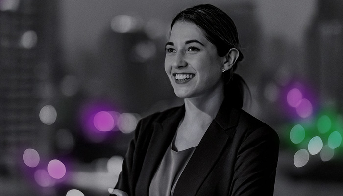 Woman photographed on balcony of office building with skyscrapers in the background