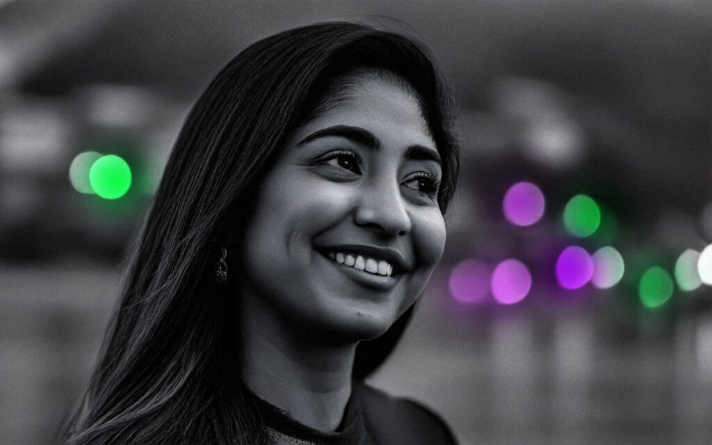 Woman smiling in mid-conversation with purple and green lights behind her