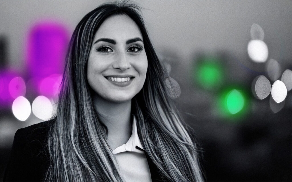 Young woman in business attire photographed on a roof terrace with sky scrapers in the background